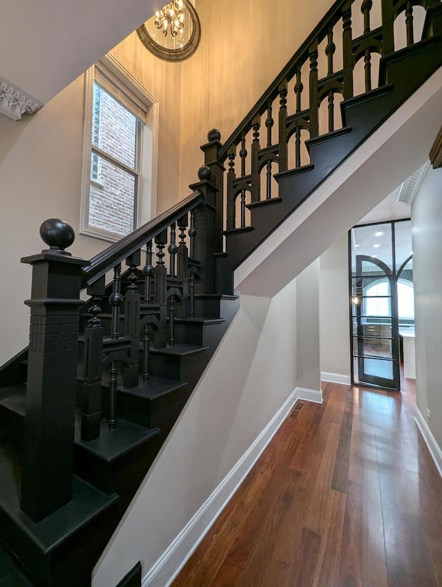 stairway featuring hardwood / wood-style floors and a notable chandelier