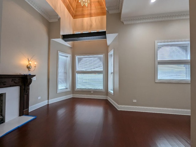 unfurnished living room featuring dark hardwood / wood-style floors, ornamental molding, and a notable chandelier