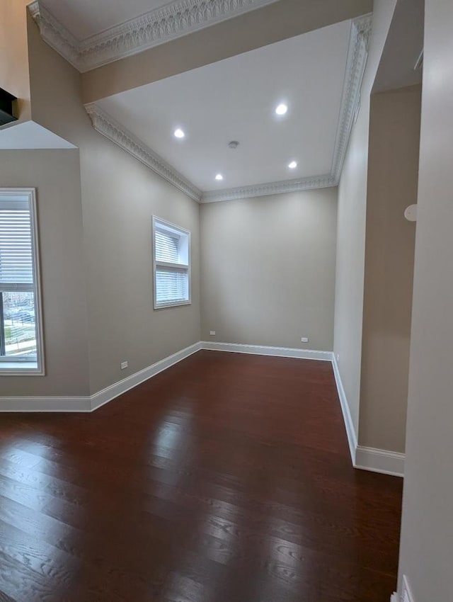 empty room with dark hardwood / wood-style floors, crown molding, and a healthy amount of sunlight