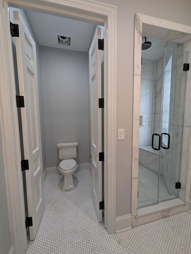 bathroom featuring tile patterned floors, an enclosed shower, and toilet