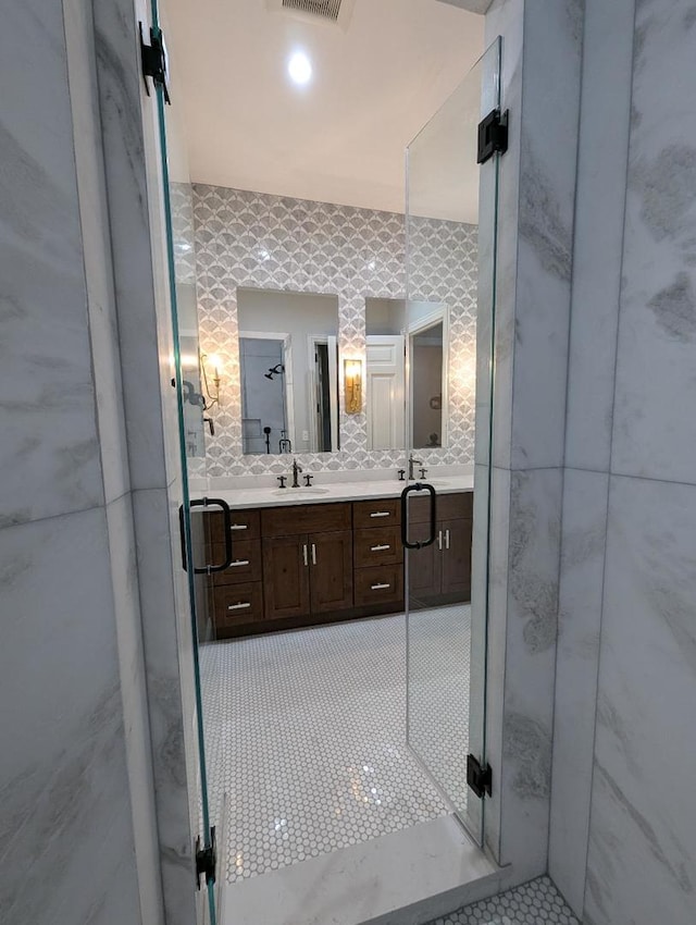 bathroom with tile patterned flooring, vanity, and walk in shower