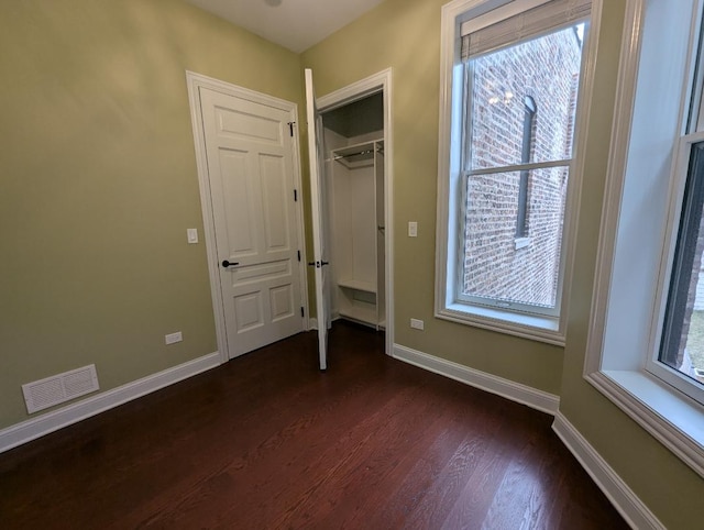 unfurnished bedroom with dark hardwood / wood-style flooring and a closet