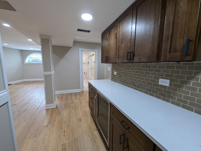 kitchen with decorative backsplash, dark brown cabinets, and light hardwood / wood-style flooring