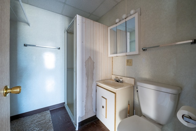 bathroom with a drop ceiling, toilet, an enclosed shower, and vanity