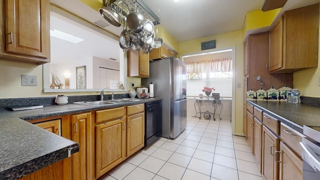 kitchen featuring sink, stainless steel refrigerator, light tile patterned floors, and black dishwasher