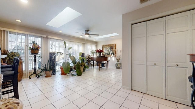 interior space featuring light tile patterned flooring, ceiling fan, and a skylight