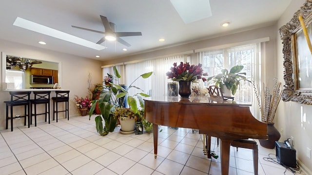 miscellaneous room with light tile patterned floors, a skylight, and ceiling fan