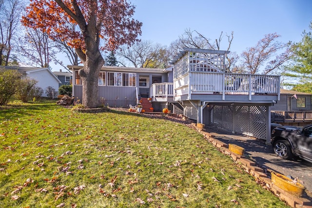 back of house featuring a lawn, a wooden deck, and a sunroom