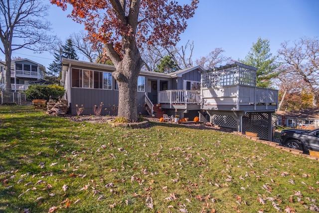 back of property featuring a sunroom, a lawn, and a wooden deck