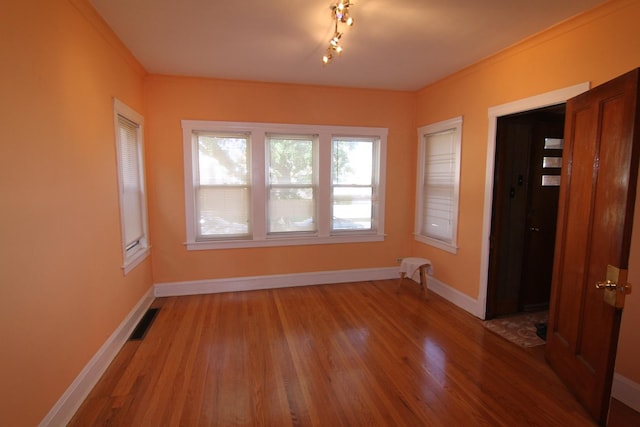 spare room featuring hardwood / wood-style floors and crown molding