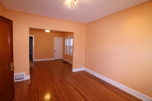 spare room featuring wood-type flooring and ornamental molding