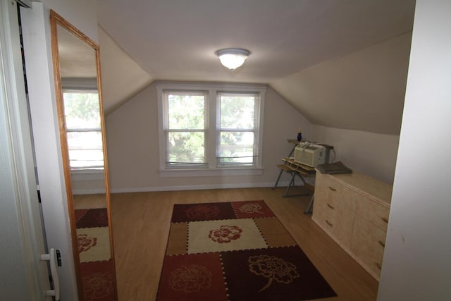 additional living space with light hardwood / wood-style floors and lofted ceiling