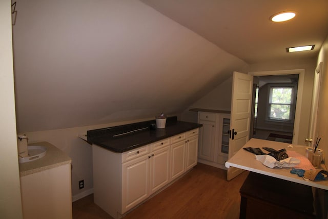 kitchen featuring white cabinets, lofted ceiling, kitchen peninsula, and dark wood-type flooring