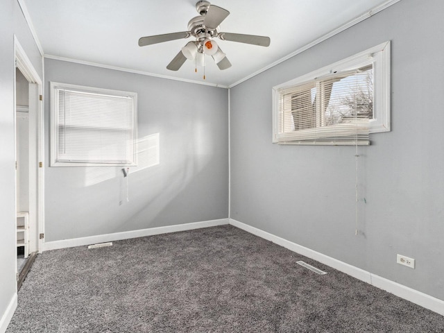 spare room with ceiling fan, crown molding, and dark colored carpet