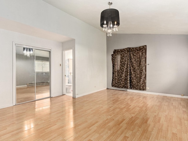 empty room featuring light wood-type flooring, an inviting chandelier, baseboard heating, and lofted ceiling