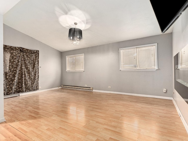 unfurnished room featuring vaulted ceiling, light hardwood / wood-style flooring, and baseboard heating