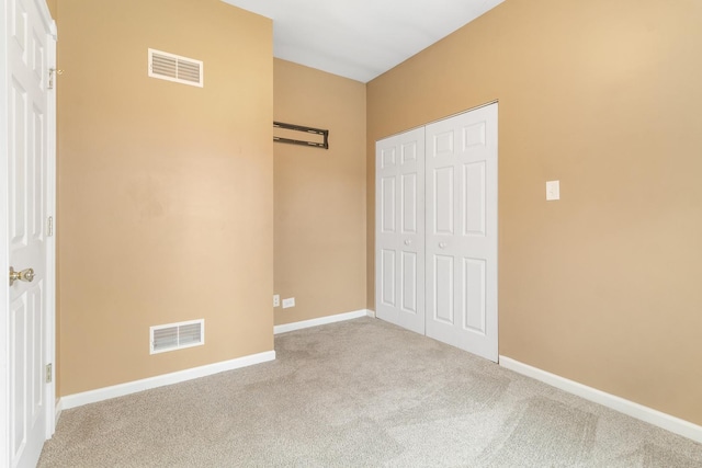 unfurnished bedroom with light carpet and a closet