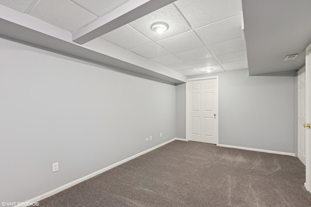 basement featuring dark carpet and a drop ceiling