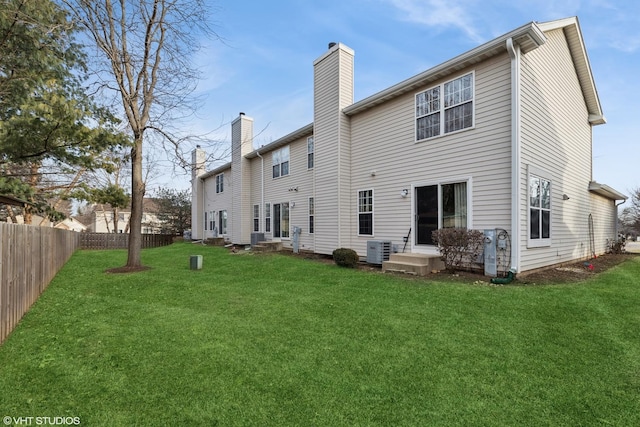 rear view of property with central AC unit and a lawn