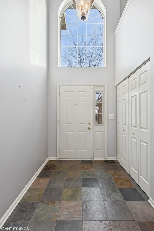 foyer entrance featuring a towering ceiling and a chandelier