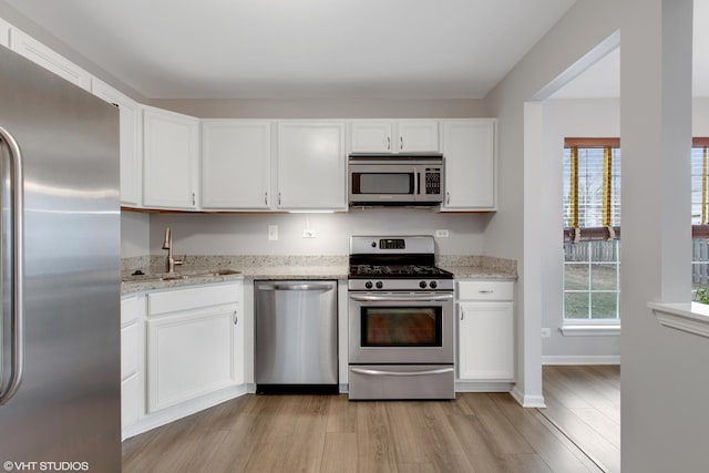 kitchen featuring white cabinetry, light stone counters, sink, and appliances with stainless steel finishes