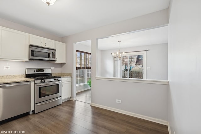 kitchen with light stone countertops, white cabinetry, stainless steel appliances, an inviting chandelier, and dark hardwood / wood-style floors