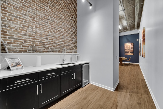 bar featuring brick wall, light hardwood / wood-style floors, and sink