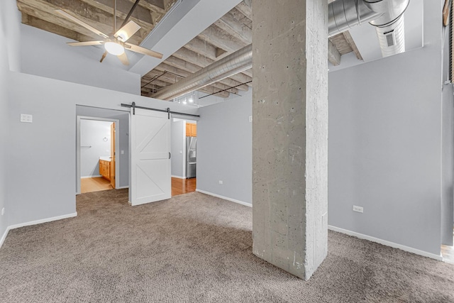 basement with stainless steel fridge, a barn door, carpet, and ceiling fan