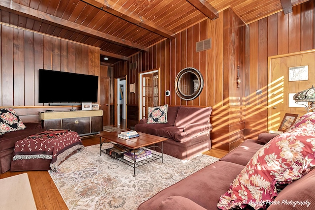 living room featuring beamed ceiling, wood-type flooring, wood ceiling, and wood walls