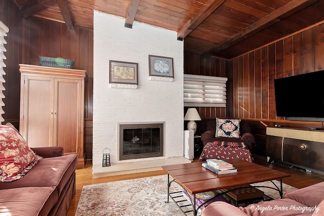 living room with hardwood / wood-style floors, beamed ceiling, wood ceiling, and a brick fireplace