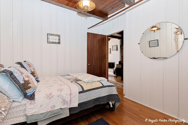 bedroom with wood-type flooring, ceiling fan, wood ceiling, and beam ceiling