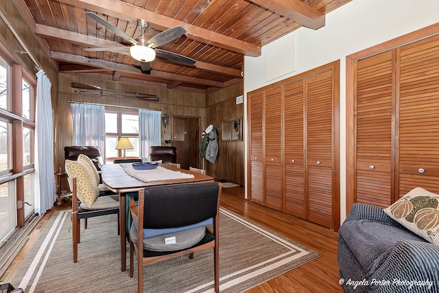 dining space with wood ceiling, ceiling fan, wooden walls, beam ceiling, and hardwood / wood-style floors