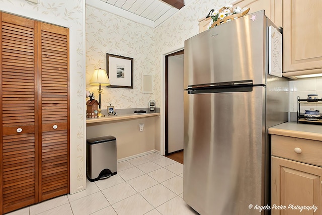 kitchen featuring decorative backsplash, light tile patterned floors, and stainless steel refrigerator