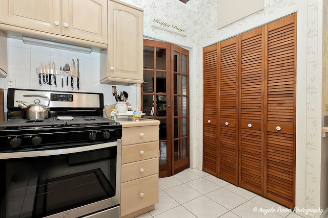 kitchen with stainless steel gas range oven, tasteful backsplash, light tile patterned floors, and french doors