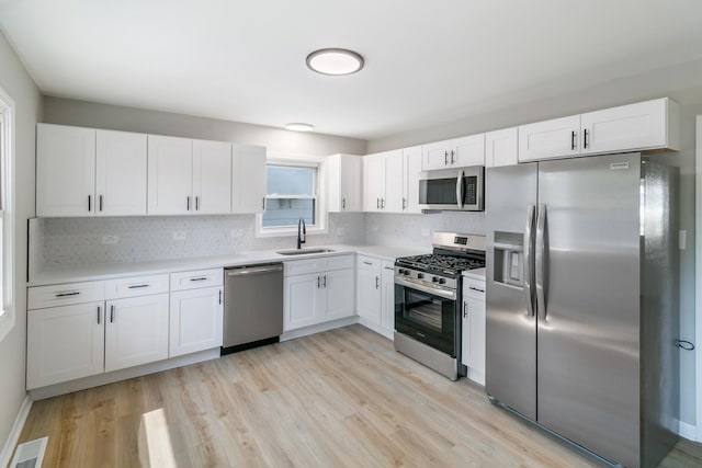 kitchen featuring white cabinets, light wood-type flooring, sink, and appliances with stainless steel finishes