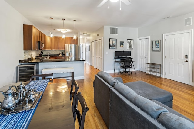 living room with wine cooler, ceiling fan, and light hardwood / wood-style floors