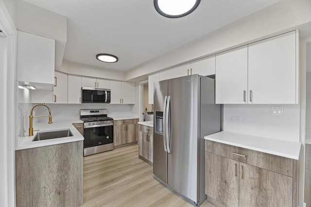 kitchen featuring stainless steel appliances, light hardwood / wood-style floors, white cabinets, and sink