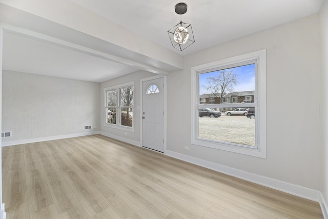 entrance foyer with light wood-type flooring, a healthy amount of sunlight, and an inviting chandelier