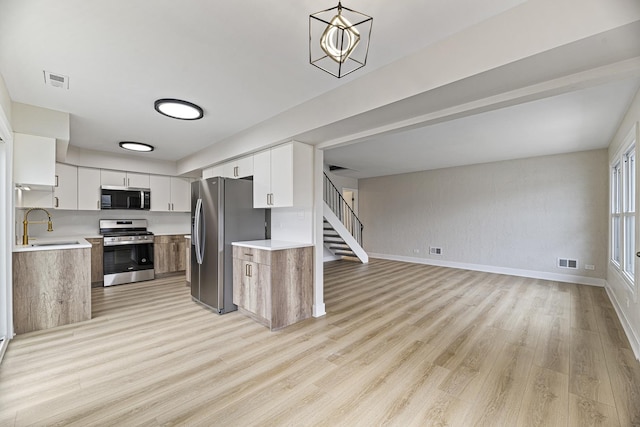 kitchen with sink, stainless steel appliances, white cabinetry, and hanging light fixtures