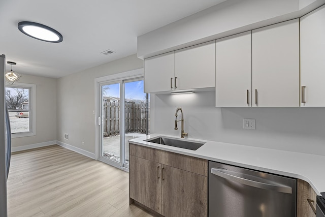 kitchen with dishwasher, pendant lighting, light hardwood / wood-style floors, white cabinets, and sink