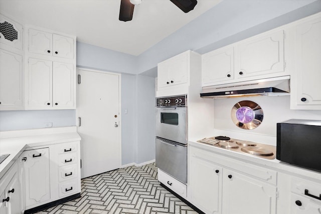 kitchen with white cabinets, multiple ovens, stovetop, and ceiling fan