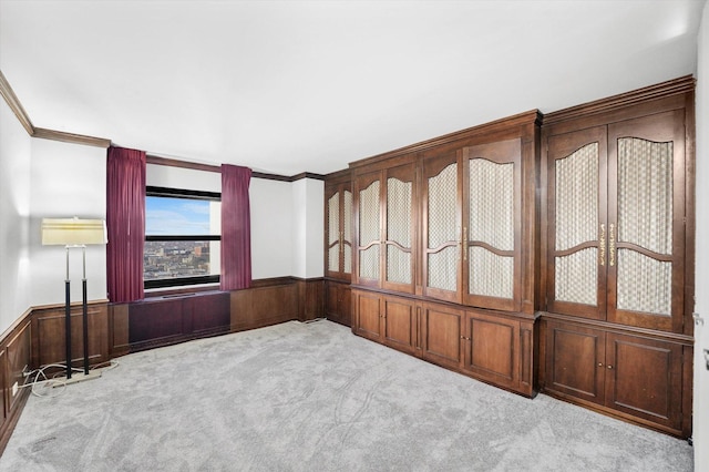 carpeted empty room with wood walls, crown molding, and french doors