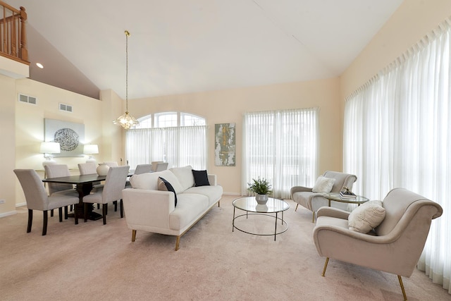 carpeted living room with a chandelier and high vaulted ceiling