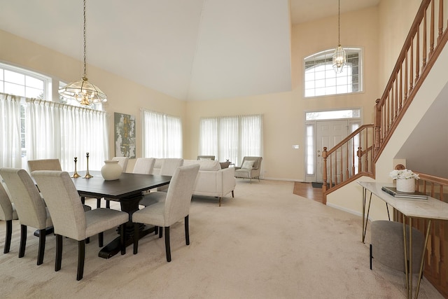 carpeted dining room with plenty of natural light, high vaulted ceiling, and a notable chandelier