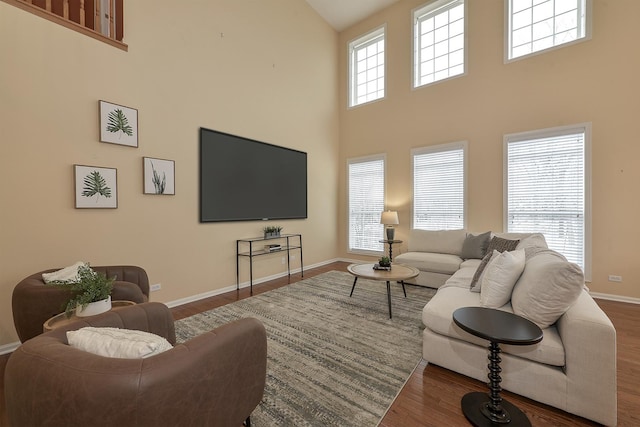 living room with dark hardwood / wood-style floors, a healthy amount of sunlight, and a high ceiling