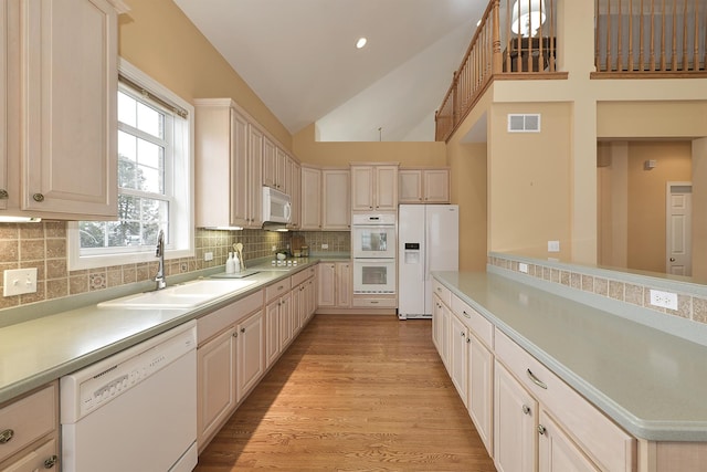 kitchen featuring sink, tasteful backsplash, high vaulted ceiling, light hardwood / wood-style floors, and white appliances