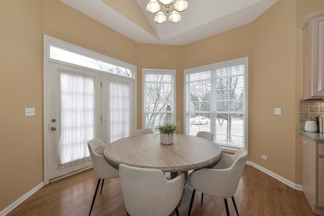 dining area featuring a chandelier, light hardwood / wood-style floors, vaulted ceiling, and plenty of natural light