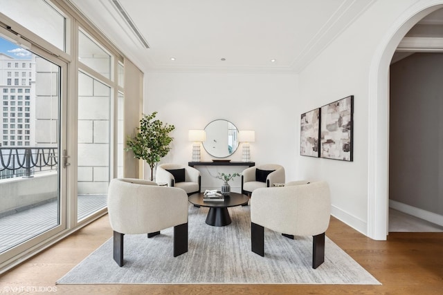 living area with ornamental molding and light hardwood / wood-style flooring