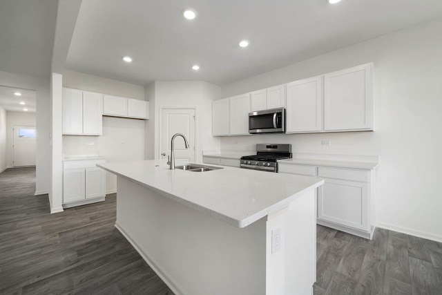 kitchen with appliances with stainless steel finishes, a kitchen island with sink, dark wood-type flooring, sink, and white cabinetry