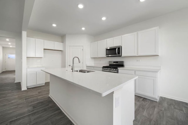 kitchen with stainless steel appliances, a kitchen island with sink, sink, dark hardwood / wood-style floors, and white cabinetry